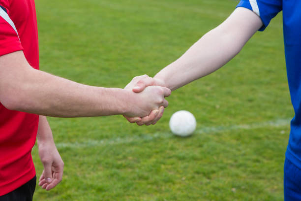 Football players in blue and red shaking hands Football players in blue and red shaking hands on a clear day gears in the sky stock pictures, royalty-free photos & images