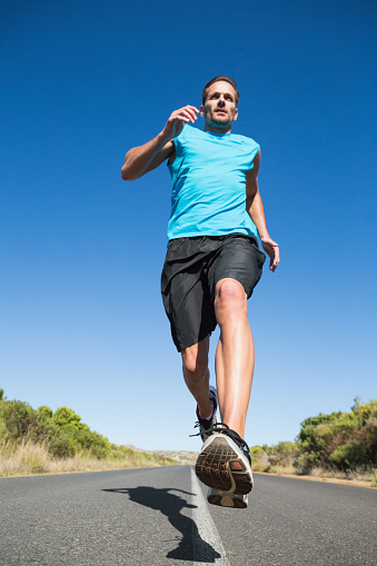 Fit man jogging on the open road on a sunny day