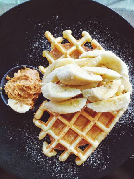 Amazing tasty dessert belgian waffles with banana and peanut butter