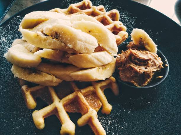 Amazing tasty dessert belgian waffles with banana and peanut butter