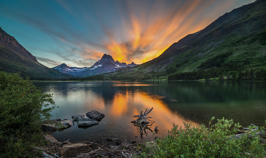 Amazing sunset with mountains, lake, forest, clouds in the sky and beautiful mirror reflections in the water. Altai, Russia