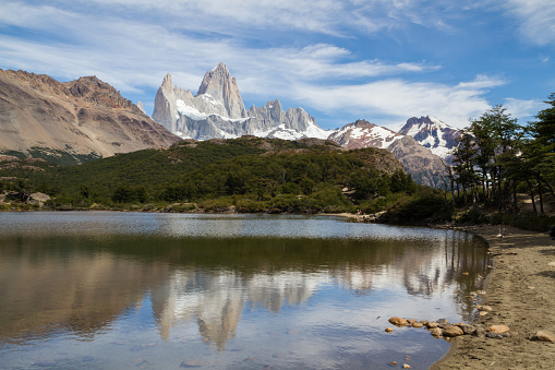 Iconic Mount Fitz Roy with some beautiful clouds in the background and a forested ridge and lake in the foreground