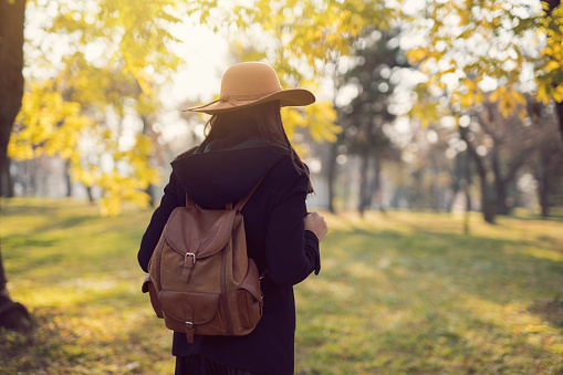 Rear view of an unrecognizable woman with a hat and backpack on her shoulders going on an adventure.