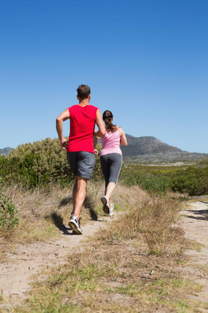 active couple jogging on country terrain - running jogging footpath cross country running imagens e fotografias de stock