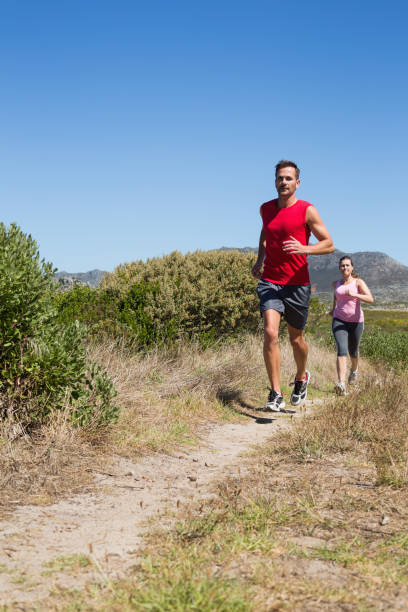 active couple jogging on country terrain - running jogging footpath cross country running imagens e fotografias de stock