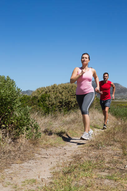 aktive paar joggen an land gelände - running jogging footpath cross country running stock-fotos und bilder