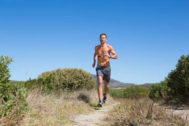 shirtless man jogging with heart rate monitor around chest - running jogging footpath cross country running imagens e fotografias de stock