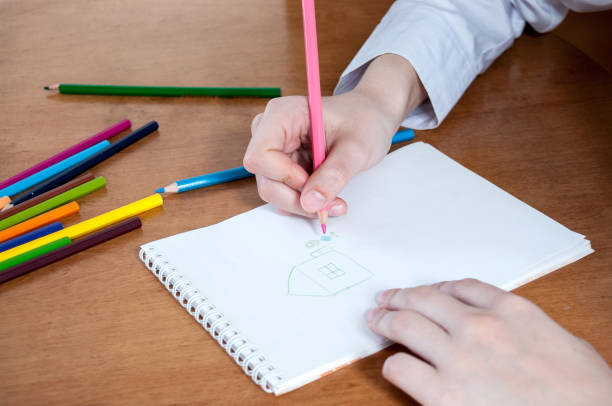istock The girl draws house with colored pencils in notebook 816630988
