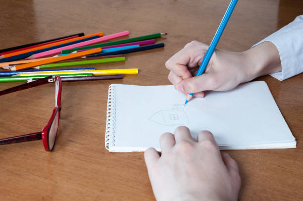 istock The girl draws house with colored pencils in notebook 816633224