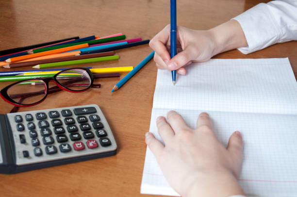 istock Student writes in notebook, on  table colored pencils and calculator 816633484