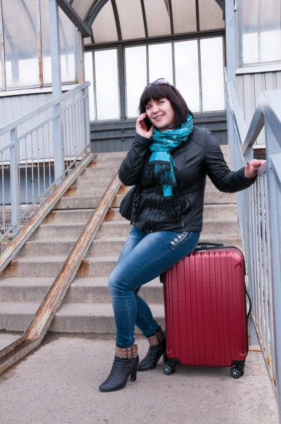 istock Girl is sitting on a suitcase talking on the phone 816636218