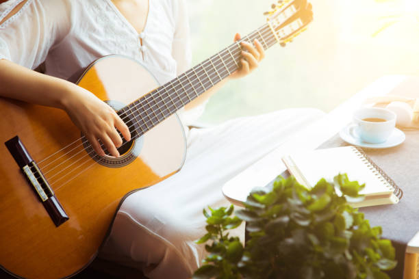 istock Young woman playing guitar at home 816689720