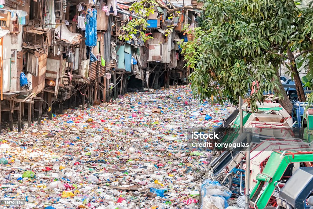 Polluted Urban River Shanties on stilts standing on garbage-filled river Pollution Stock Photo