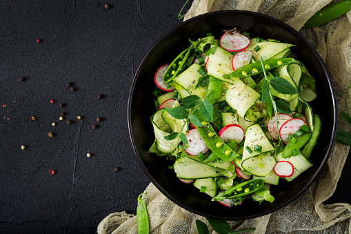 Fresh salad of cucumbers, radishes, green peas and herbs. Flat lay. Top view