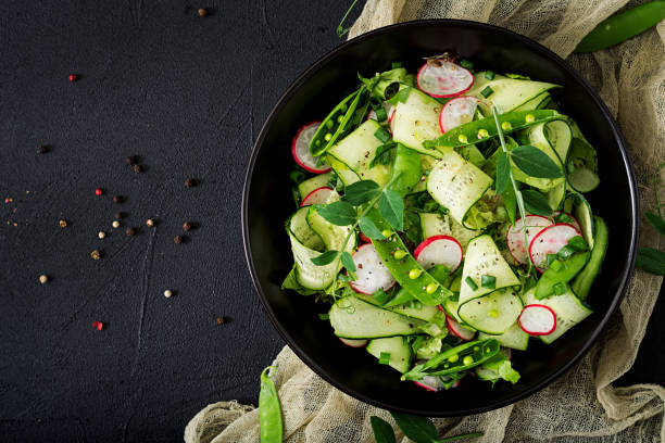 Fresh salad of cucumbers, radishes, green peas and herbs. Flat lay. Top view stock photo