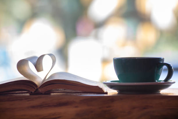A white cup of black coffee and book on wooden table
