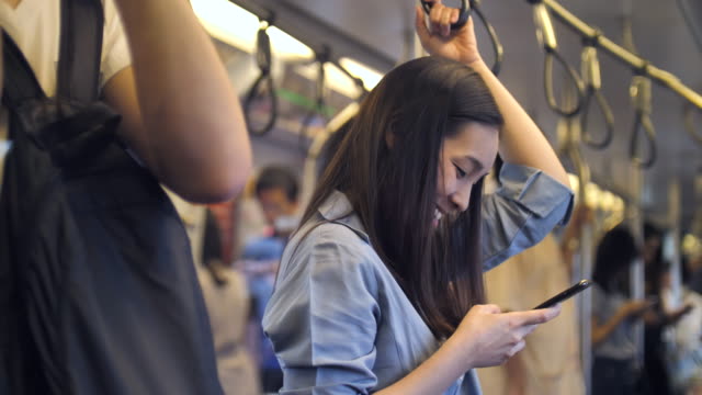 Young woman using phone for social networking on train, Slow motion