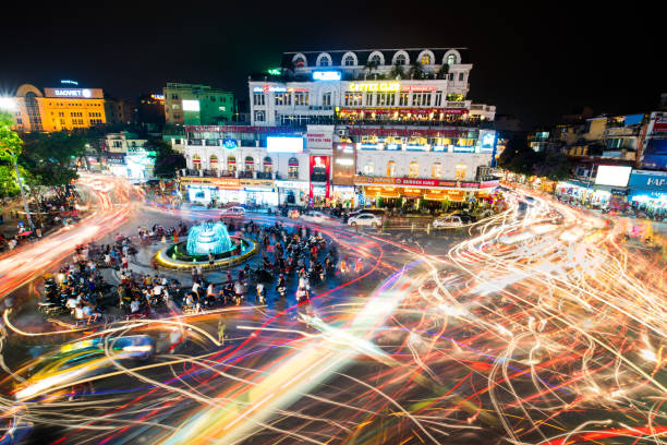 People and vehicles light trails crowd on busy intersection locating next to Hoan Kiem lake. HANOI, VIETNAM - MAY 21, 2016: People and vehicles  hanoi stock pictures, royalty-free photos & images
