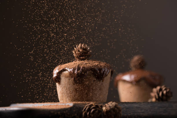 istock Chocolate muffins, decorated with a small cone on a dark wooden background. Cupcakes are poured with dark chocolate and cocoa powder. Cupcakes with unusual decoration. Low key 816798470