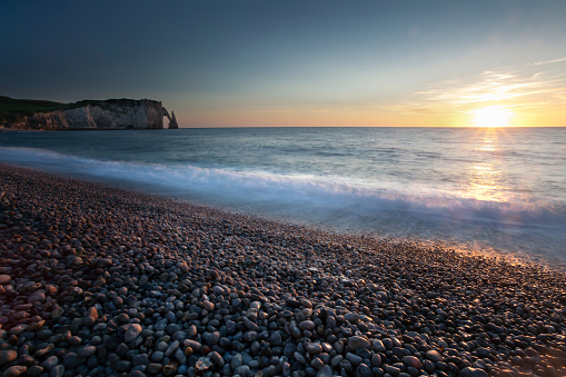 Sunset at the pebbled beach, Porte d'Aval and L'Aiguille at Etretat, a commune in the Seine-Maritime department in the Normandy region of north western France