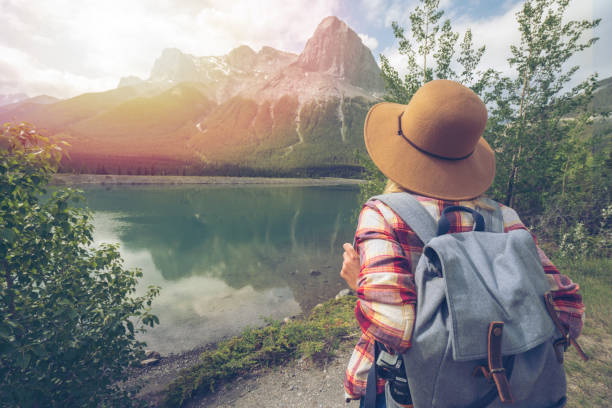 Young woman hiker contemplating mountain lake landscape in Springtime. People in nature concept