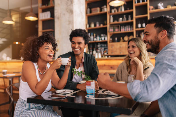 Young friends having a great time in cafe Young friends having a great time in restaurant. Multiracial group of young people sitting in a coffee shop and smiling. coffe to stock pictures, royalty-free photos & images