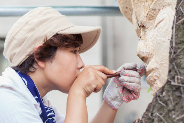 Close-Up Photo Of Sculptor A close-up portrait of a Japanese woman sculptor. She is carving buddha face on a tree. sculptor stock pictures, royalty-free photos & images