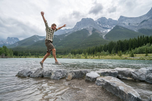 istock Hiker jumps rock to rock on mountain lake 816849788