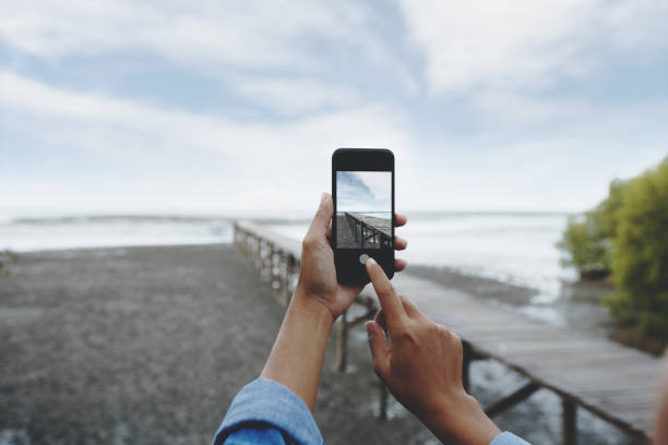 enfoque selectivo en mano con teléfono inteligente tomar fotos del paisaje - smart phone fotos fotografías e imágenes de stock