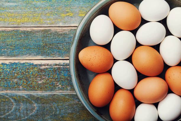 istock White and brown chicken eggs in vintage bowl on rustic wooden table top view. 816863390