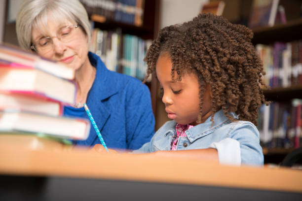 istock Teacher, mentor helps elementary-age schoolgirl with homework. 816892536