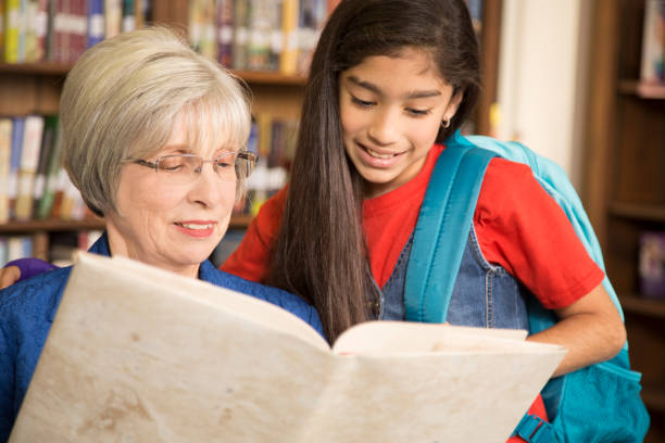 istock Teacher, librarian reads book to elementary student in library or classroom. 816893224