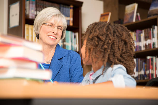 istock Teacher, mentor helps elementary-age schoolgirl with homework. 816895412