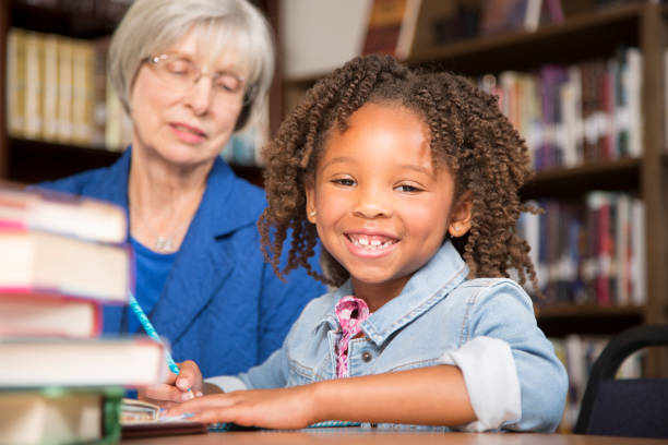 istock Teacher, mentor helps elementary-age schoolgirl with homework. 816897664