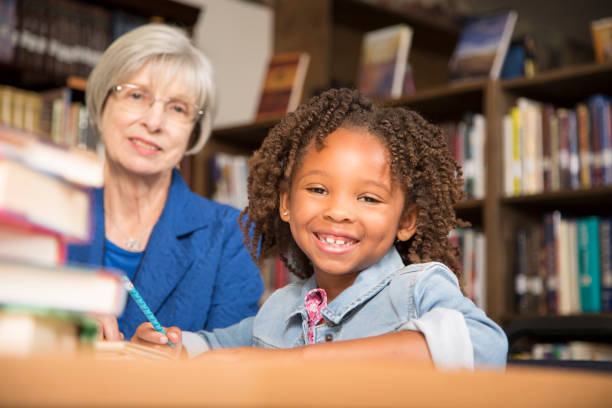 istock Teacher, mentor helps elementary-age schoolgirl with homework. 816897790