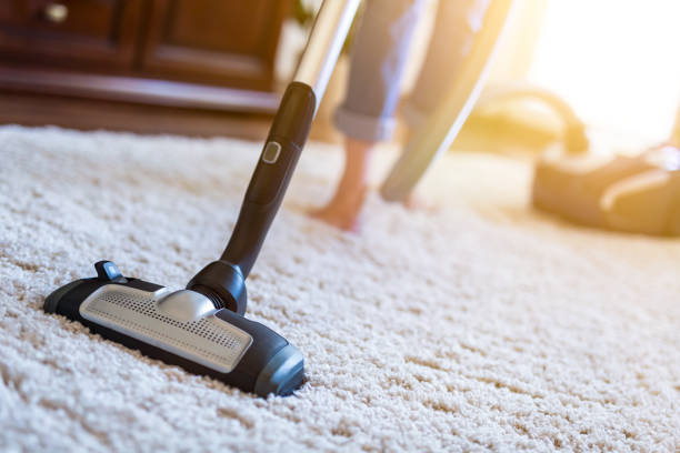donna che usa un aspirapolvere mentre pulisce il tappeto in casa. - cleaning house cleaner home interior foto e immagini stock