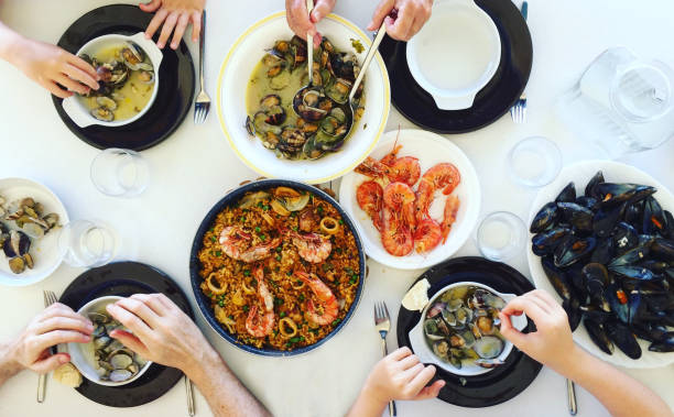 семья ест паэлью и морепродукты. вид сверху. - tapas food spain gourmet стоковые фото и изображения