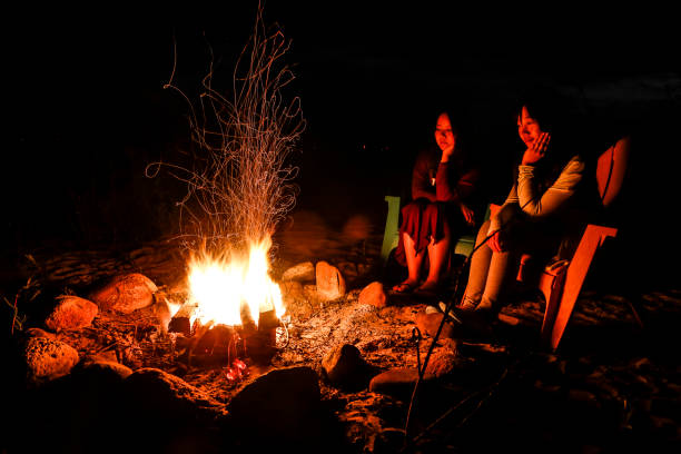 istock Two young women sit by a campfire on the beach 816949384