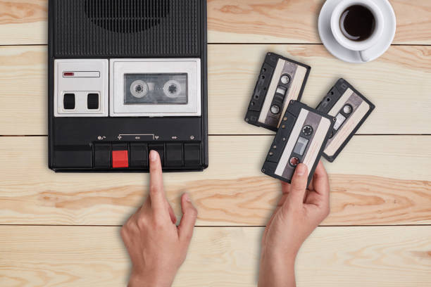 istock Retro stuff, old items, memories. Hands switching on old tape cassette recorder and holding three cassettes choosing which song to reproduce. Woman listening to old songs remebering her youth 816954424