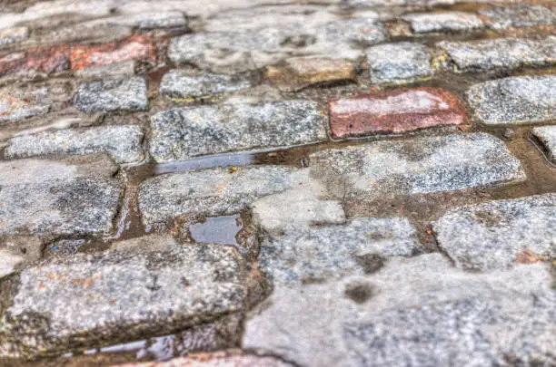 Macro closeup of wet, puddles and cobblestone street rocks with colorful texture and detail