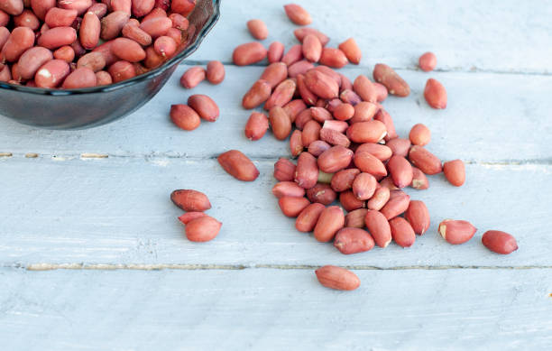 istock Many peanut kernels on a wooden background are gray-blue. 817013092