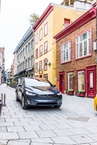 tesla modelo x dirigindo na estrada de paralelepípedos na baixa da cidade velha rua chamada rua sault-au-matelot por restaurantes, lojas e lojas de souvenirs de azul - lower downtown - fotografias e filmes do acervo