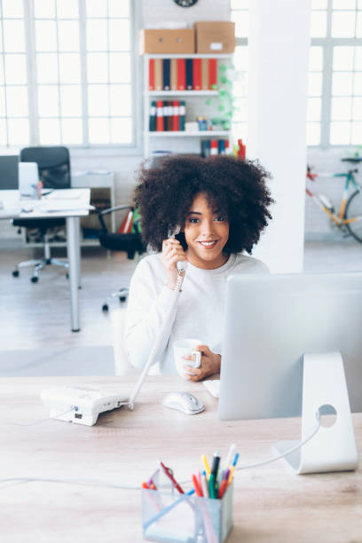 istock Smiling female assistant using landline phone in modern office 817026438