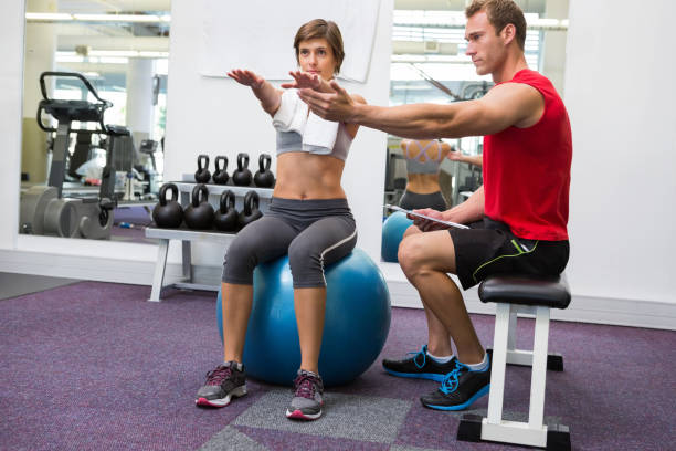 istock Personal trainer with client sitting straight on exercise ball 817031552