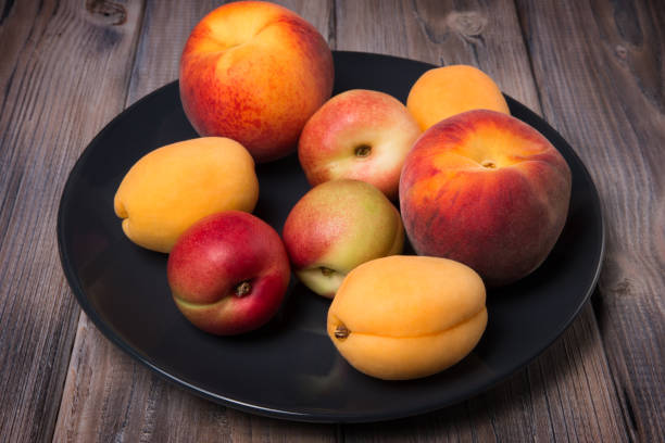 istock Peaches, apricots and nectarines on a black plate on a wooden background 817069046