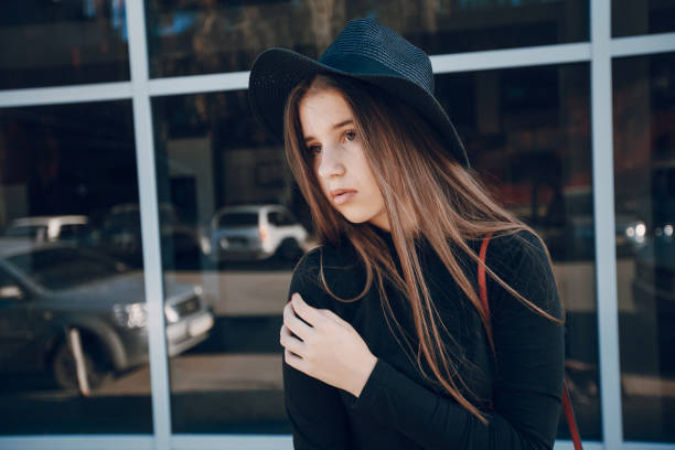girl with long hair and skirt stands near a high wall