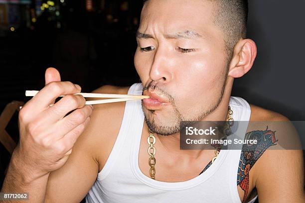 Hombre Joven Comiendo Con Palillos Chinos Foto de stock y más banco de imágenes de Adulto - Adulto, Adulto joven, Barba de tres días