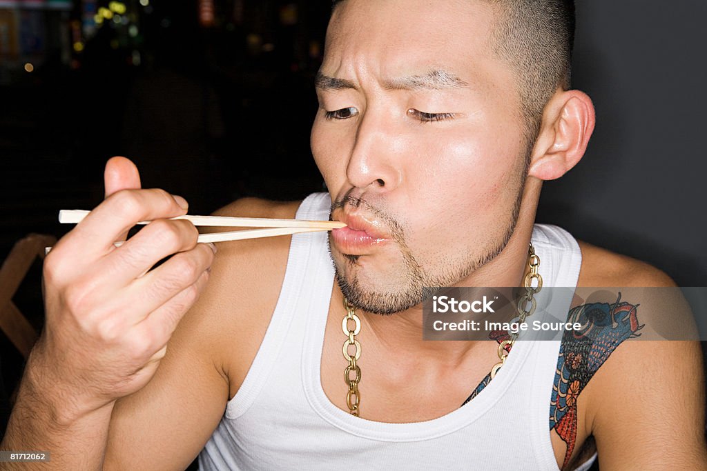 Giovane uomo mangiare con Bacchette cinesi - Foto stock royalty-free di Adulto