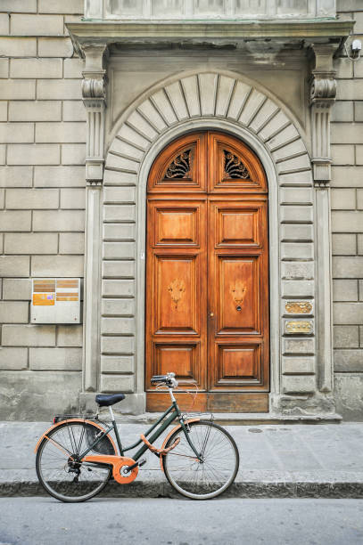 A bicycle stands against the curb in front of the door to a residence in Florence, Italy