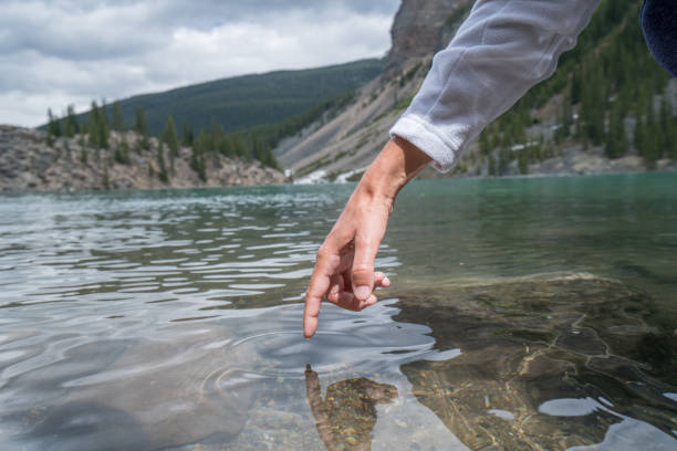 istock Finger touches surface of mountain lake 817172378